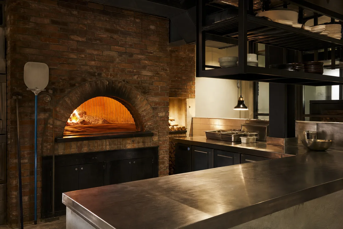 Four à bois et cuisine ouverte dans une pizzeria au décor industriel